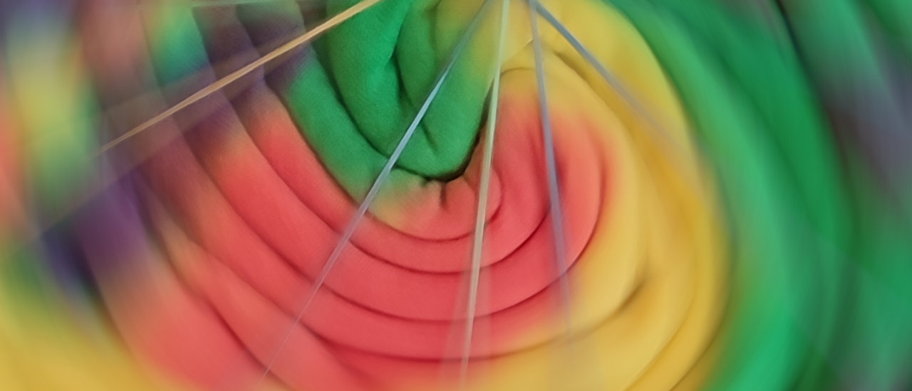 Ein großes Bannerbild, auf dem eine bunt gefärbte Stoffspirale zu sehen ist